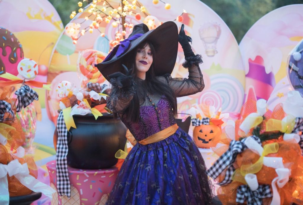 Woman dressed like a witch in front of colorful halloween decor Halloween at the Fairmont Grand Del Mar - Things to do on Halloween in San Diego