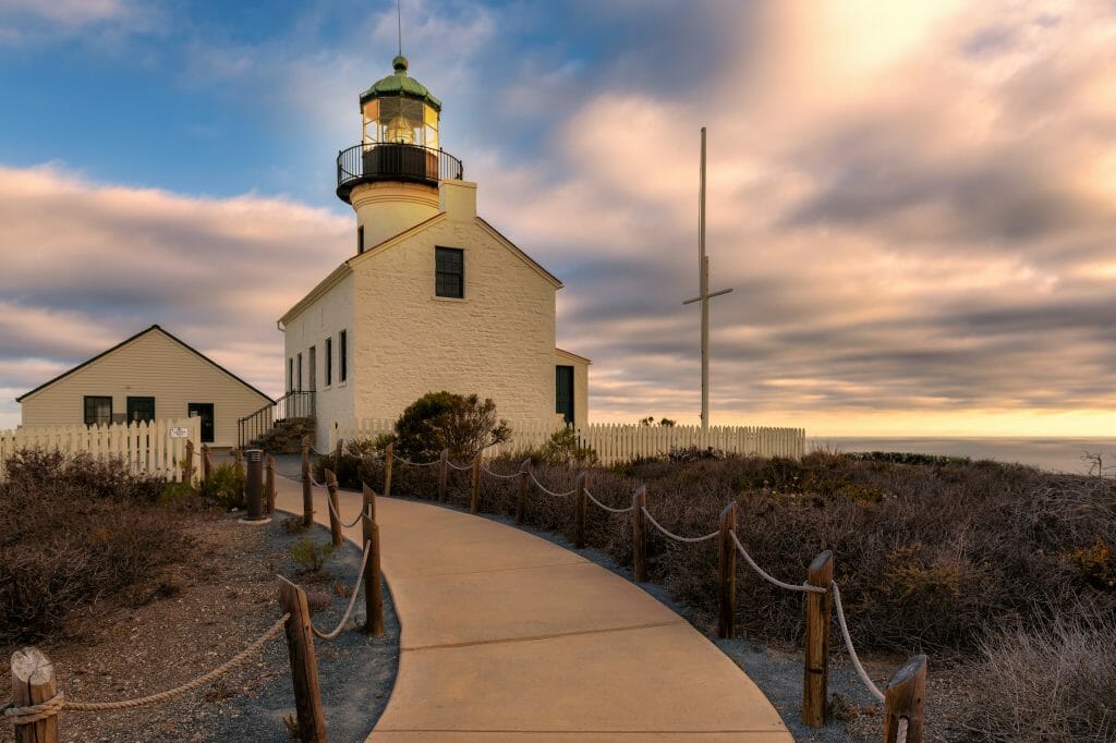 The sunsets behind the cliffs an old lighthouse sits upon it