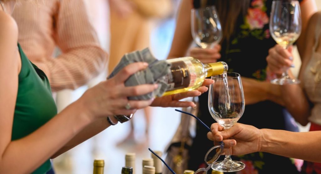 Close up of woman pouring a white wine into a wine glass at a wine tasting festival. June in San Diego