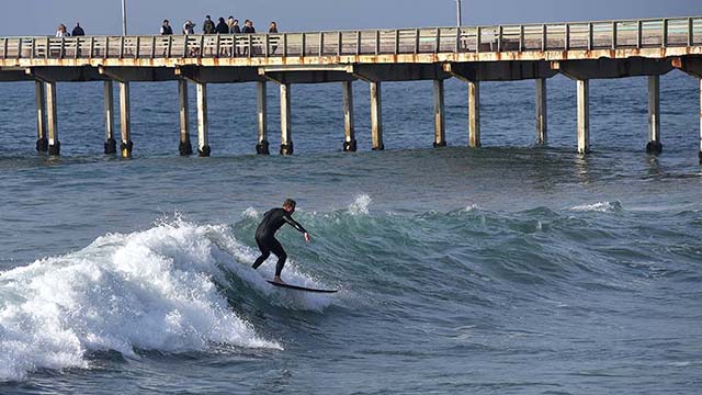A surfer hits at the waves by Ocean Beach Pier.