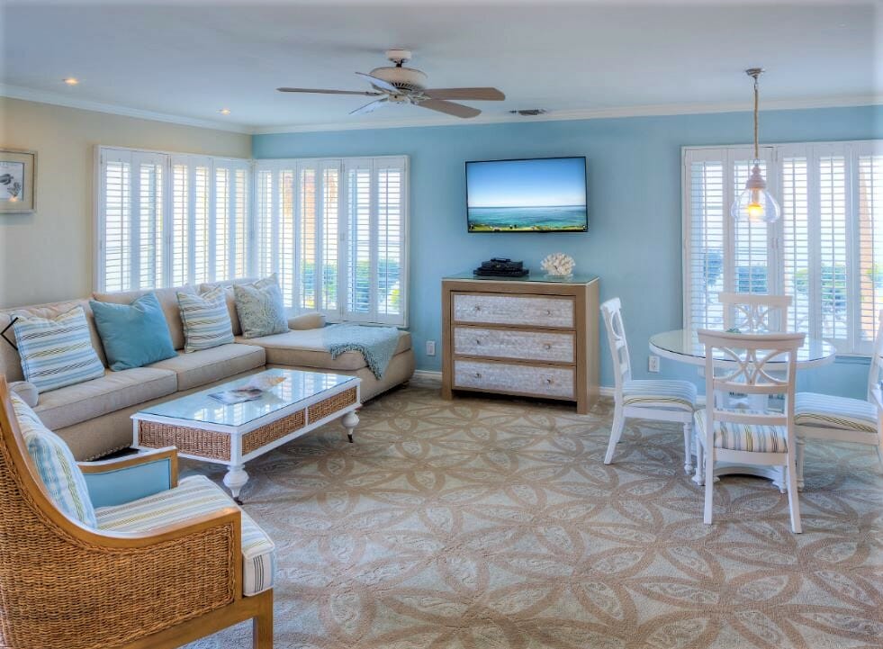 Hotel Suite at the Scripps Inn La Jolla. It features a large couch, a white table with chairs and a blue and tan colored ocean inspired color scheme and decor.
