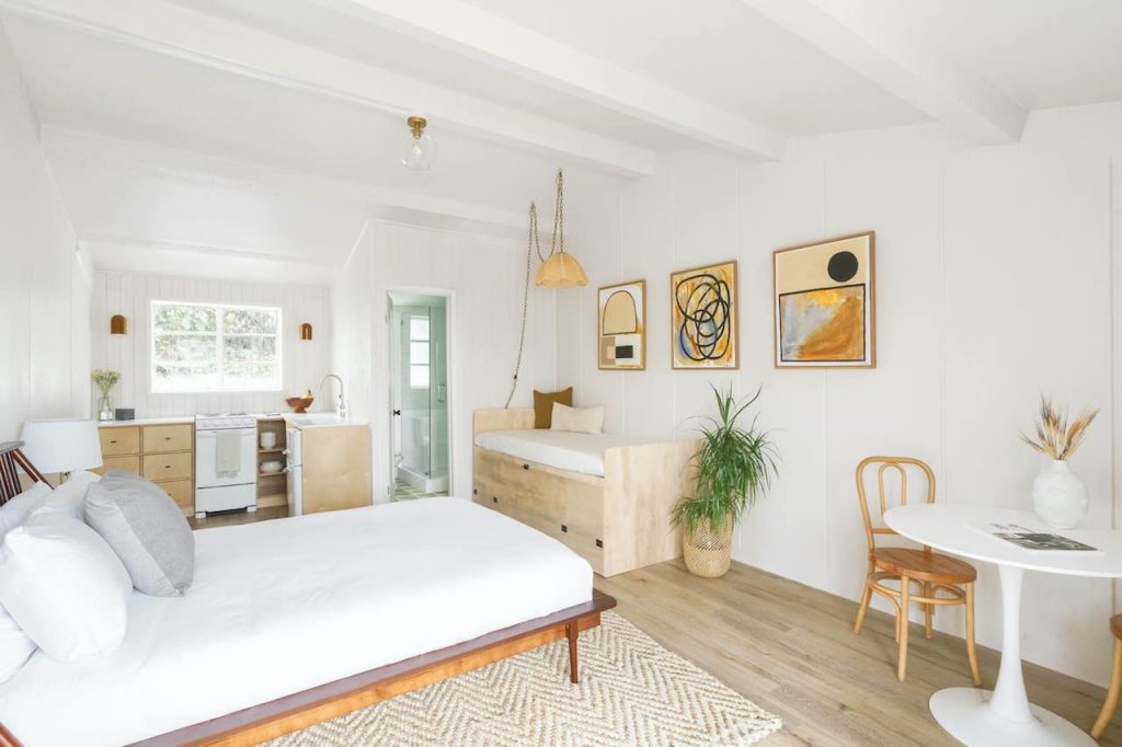 Modern, bright white hotel room with beachy finishes, cozy rug, large bed, seating areas, and small kitchenette. Green Room Hotel, Oceanside hotels.