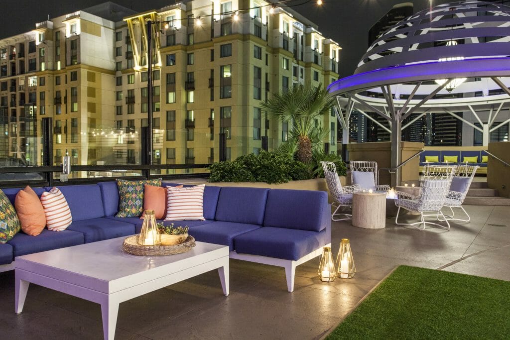 Rooftop bar at the Kimpton Solamar in San Diego with white outdoor couches with blue cushions on green fake grass