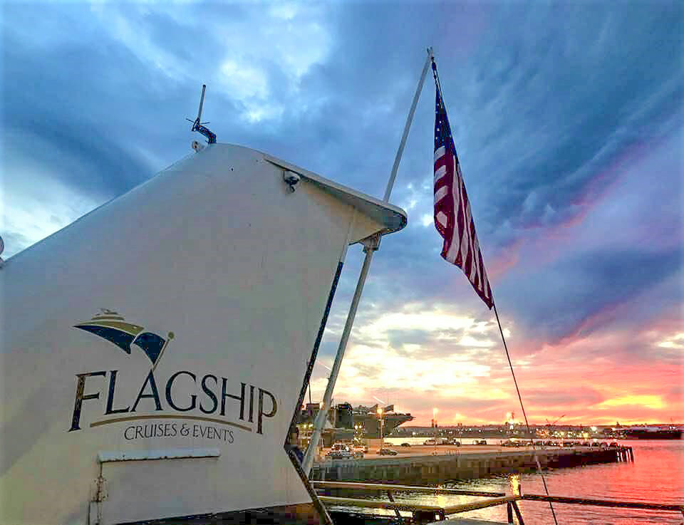 Tail of Flagship cruise ship with American flag in the foreground and a stunning sunset in the background n