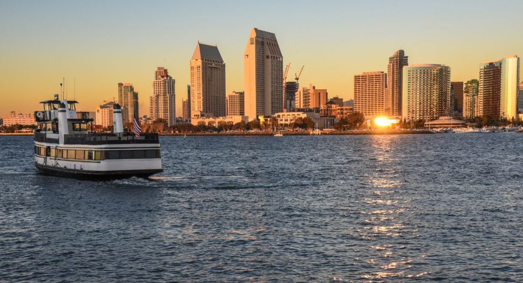 Ferry boat on calm waters of San Diego Bay with downtown San Diego skyline in background during sunset. Coronado Ferry, Coronado Ferry Landing.