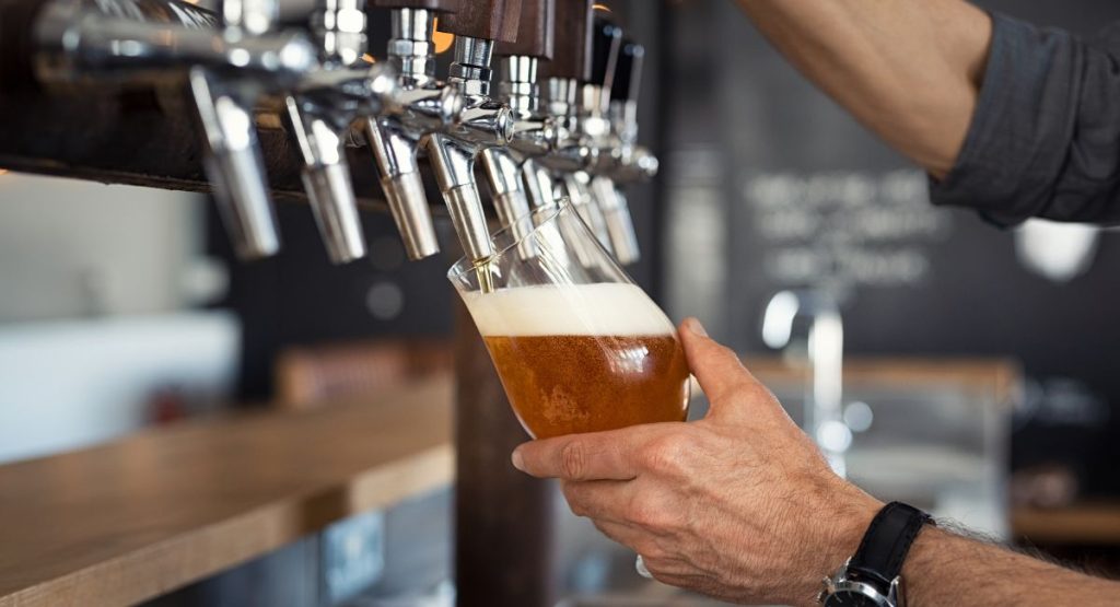 Bartender pouring craft beer at small brewery. Brewery tours in San Diego