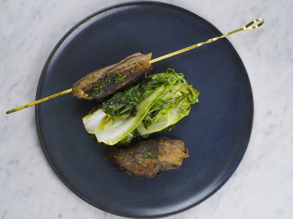 overhead shot of black plate with two pieces of duck with whole leaves of lettuce in the middle