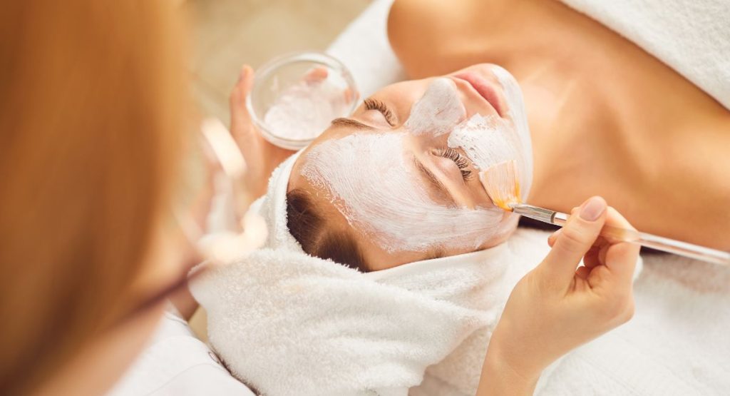 Close up of woman in white towels receiving facial from technician at spa. San Diego Spas.