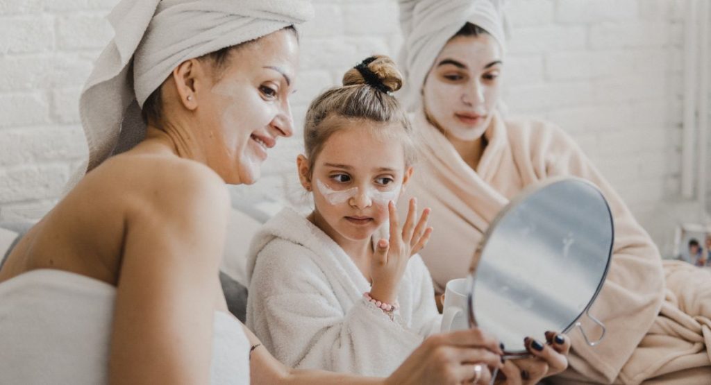 Two women with young girl having spa day in robes and towels while doing face masks. Day Spas in San Diego.