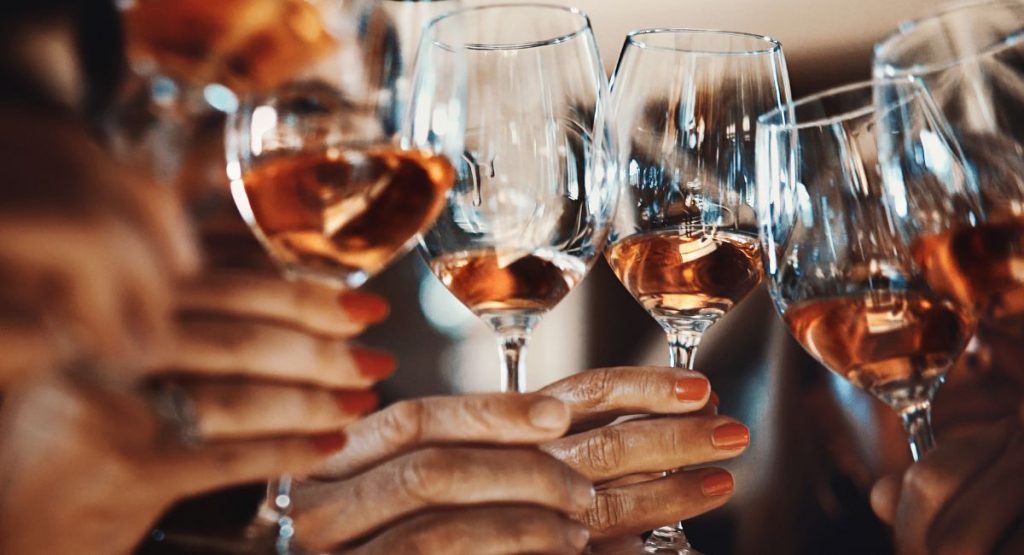 Women cheers-ing wine glasses with rose wine. Little Italy Wine Sampling and Food Tour San Diego.