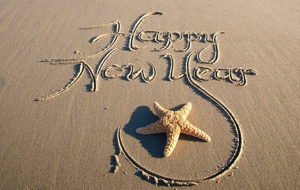 Happ New Year written in the sand, decorated with starfish - New Years Eve San Diego