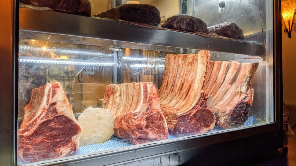 Steaks in a glass fridge on display at Greystone San Diego