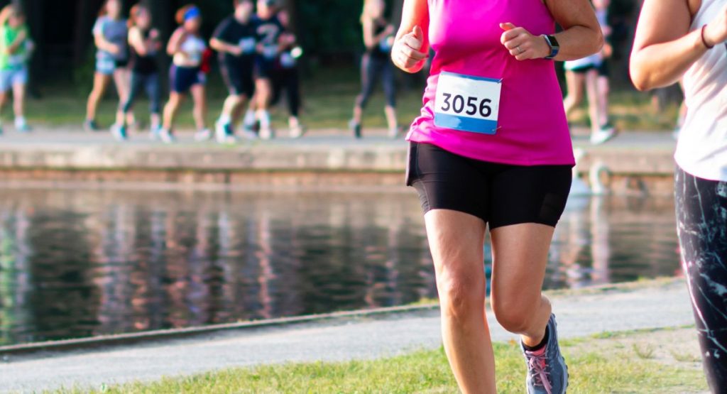 woman wearing pink and other runners in the background for San Diego 5k breast cancer