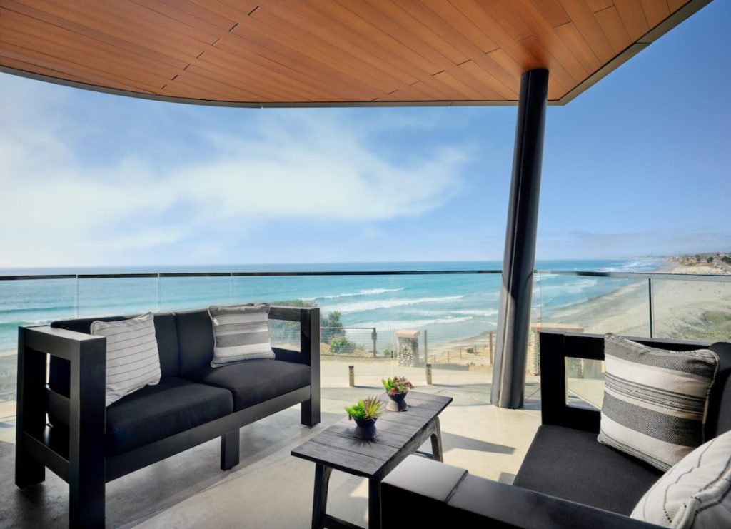 Hotel balcony with modern outdoor furnishings and sweeping Pacific Ocean views on sunny summer day. Alila Marea Hotel.