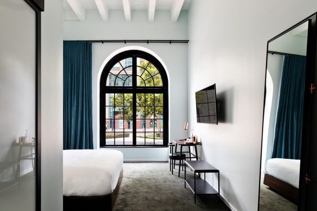 Luxury hotel room with king size bed, large mirror, and oversized, floor to ceiling window with black trim. The Guild Hotel. Boutique hotels in San Diego