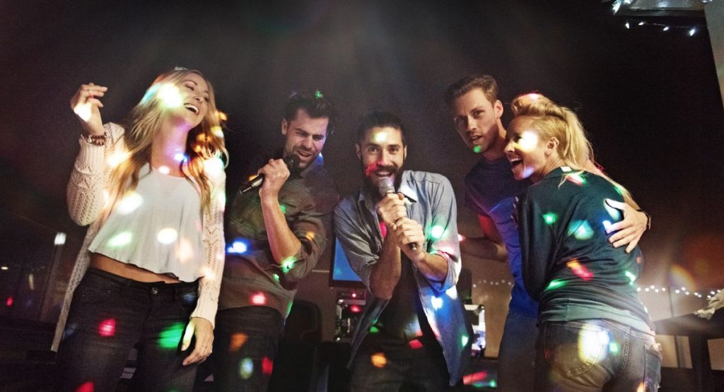 Group of people smiling and singing at karaoke in a bar. Karaoke in San Diego.