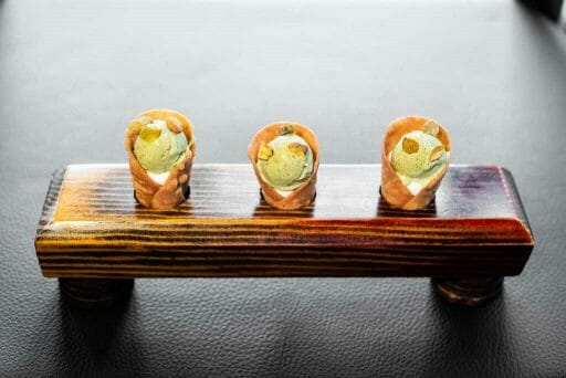 A sushi tray with 3 canoli cones filled with white and green cream