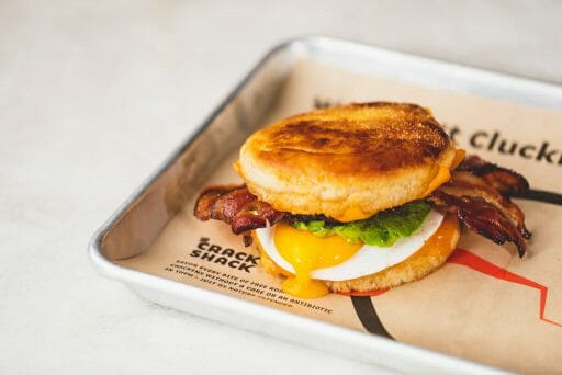 Bacon sticking out of an english muffin with a runny egg on top