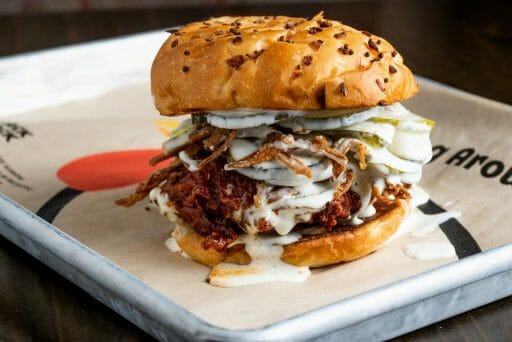 An overstuffed chicken burger on a little silver pan lined with brown parchments