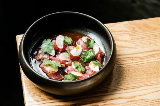 a black bowl filled with colorful food neatly placed in broth