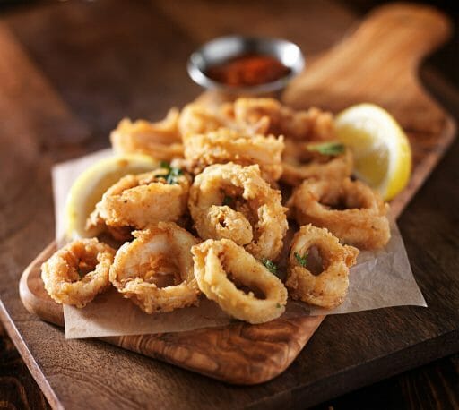 fried calamari squid appetizer on wooden serving tray