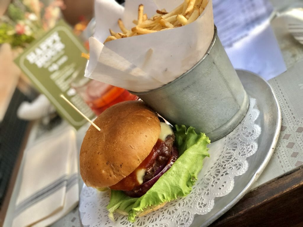 Burger on a metal plate with a metal bucket full of fries