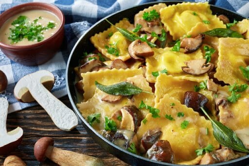 homemade ravioli stuffed with ricotta cheese cooked in creamy garlic mushrooms sauce in a skillet, close-up