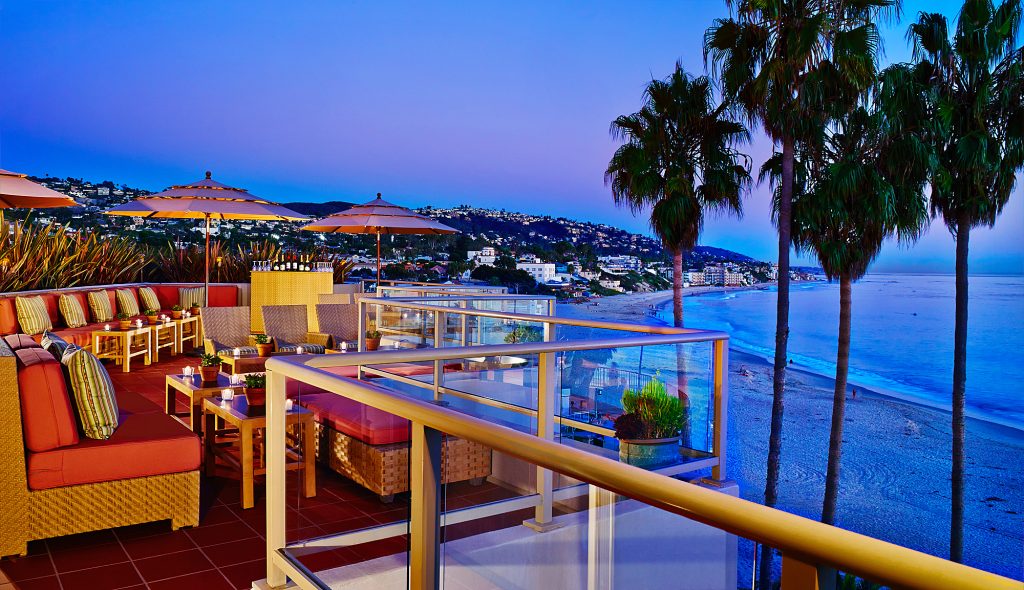 Rooftop terrace overlooking beach and palm trees at dusk