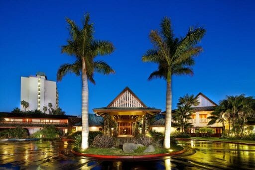 Driveway of Catamaran Resort during blue hour with two palm trees in the foreground and the hotel entrance in the background