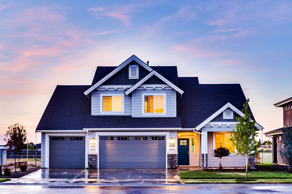 Front of a house at twilight. Wet pavement. Sky. 1 Car Garage, 2 car garage, 3 car garage. Front door. Medium trees. Windows. Vinyl Siding.  stone exterior