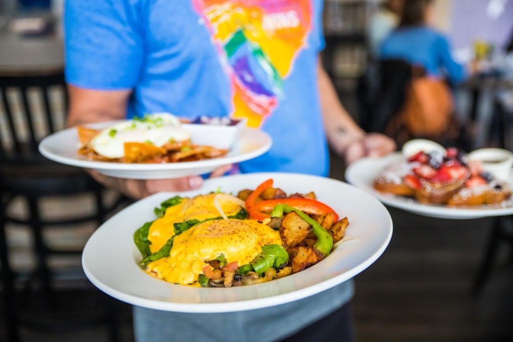 Waiter holding three plates of breakfast entrees. Harley Gray Kitchen & Bar.