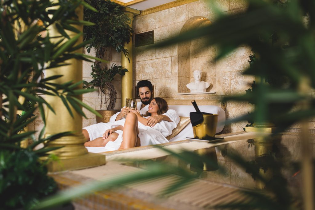 Beautiful young couple enjoying and relaxing in SPA center and drinking wine