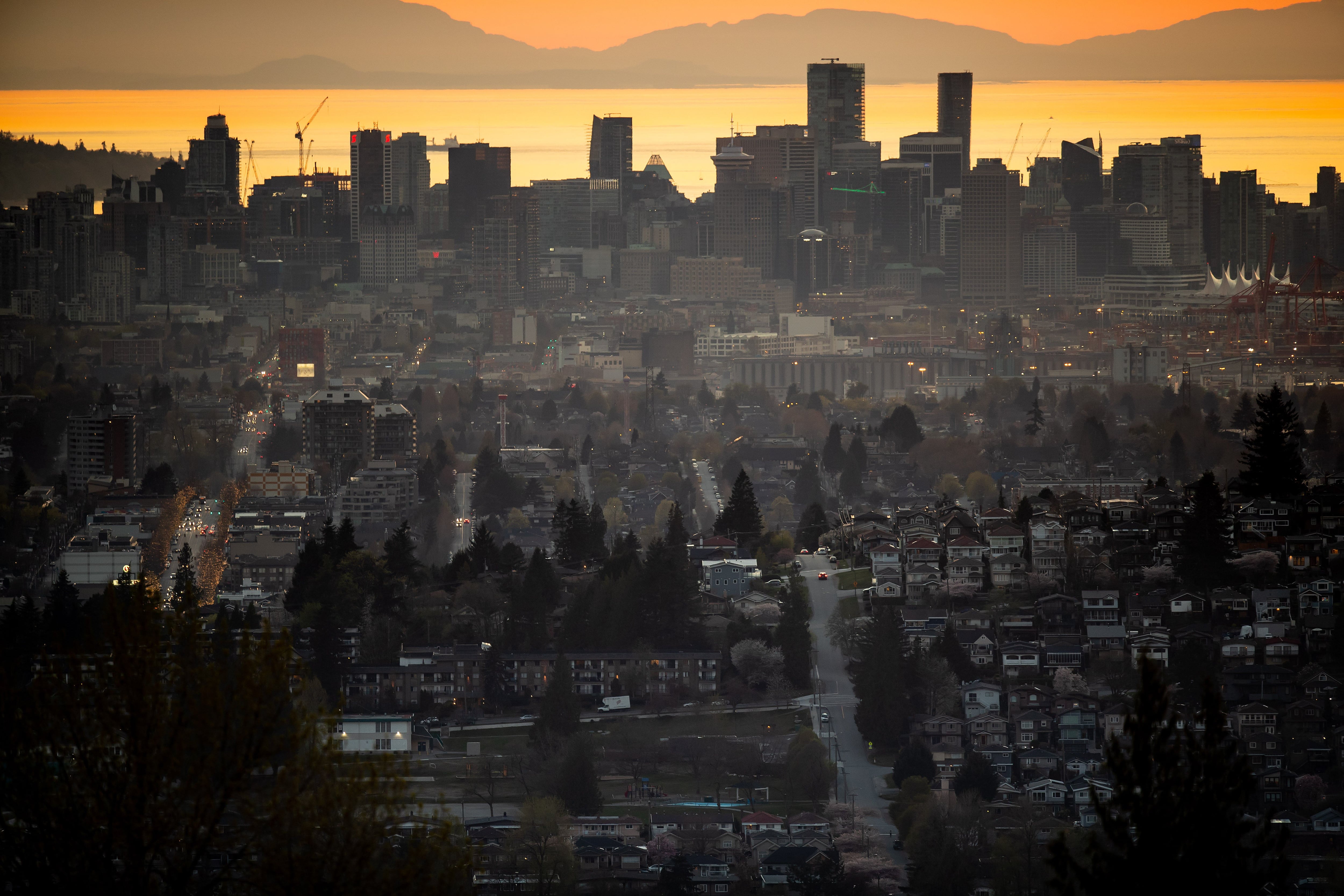 The downtown Vancouver skyline is seen at sunset, as houses line a hillside in Burnaby, B.C., on April 17, 2021. 