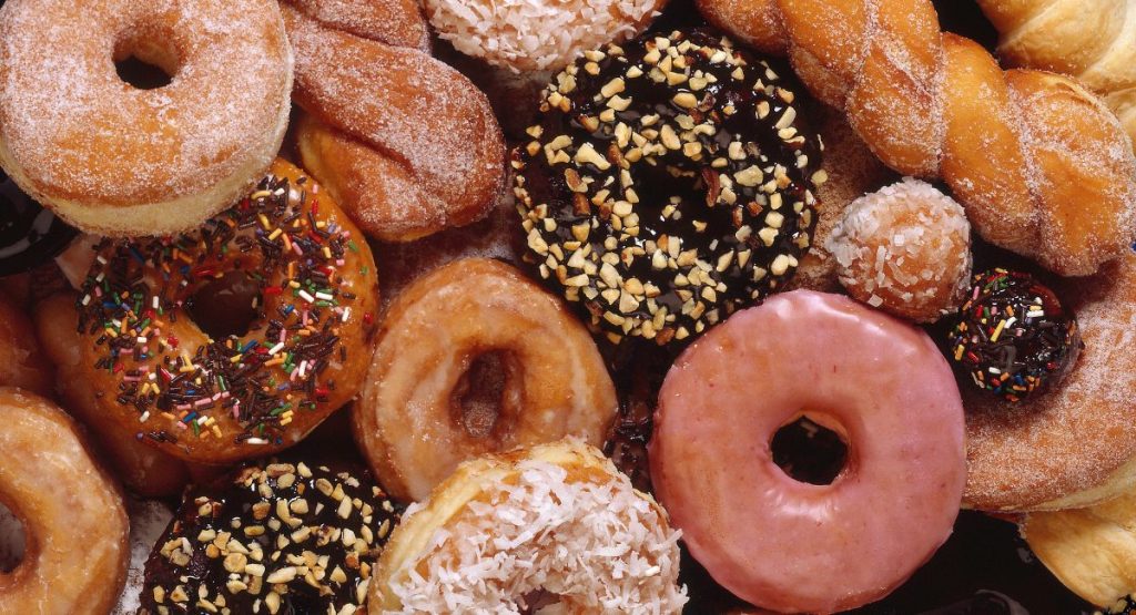 Close up of colorful donuts, pink glazed donuts, twisted donuts, sprinkle donuts.