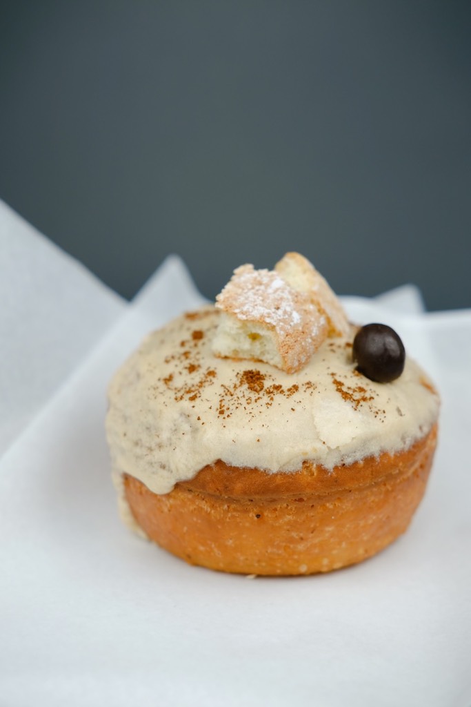 Close up of cream filled donut with white frosting. Nomad Donuts, donuts near me.