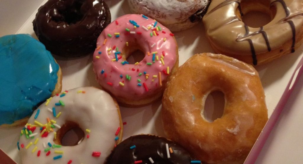 Box of colorful, frosting covered donuts with sprinkles. Best donuts in San Diego.