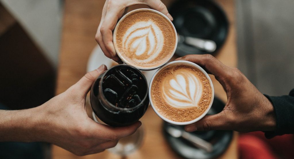 Group of people cheers-ing coffee cups. Coffee Shops San Diego.