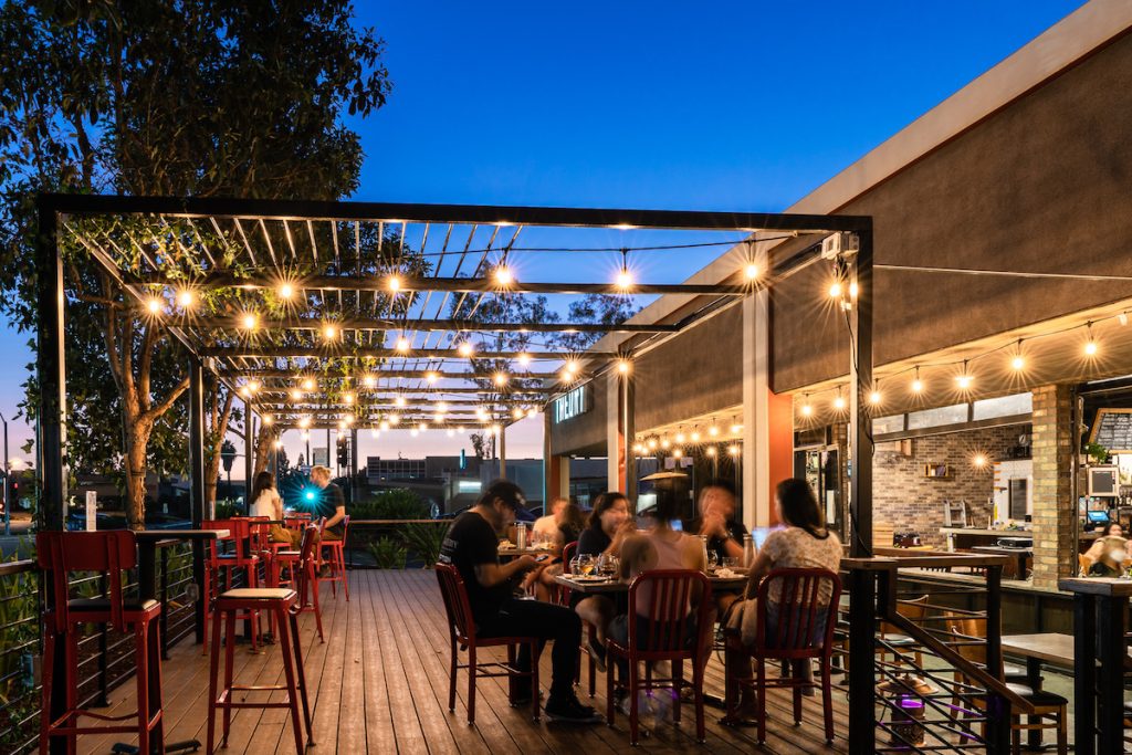 Diners on outdoor patio with string lights at night. Common Theory Public House, Dog friendly restaurants San Diego.