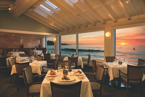 The sun setting out the window over the water with the peaceful dining room empty