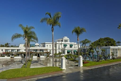 The outside of a beautiful white hotel with palm trees all around