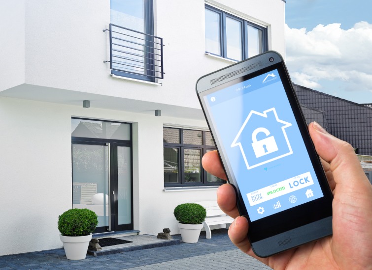 A person holding a smart phone in front of a house.