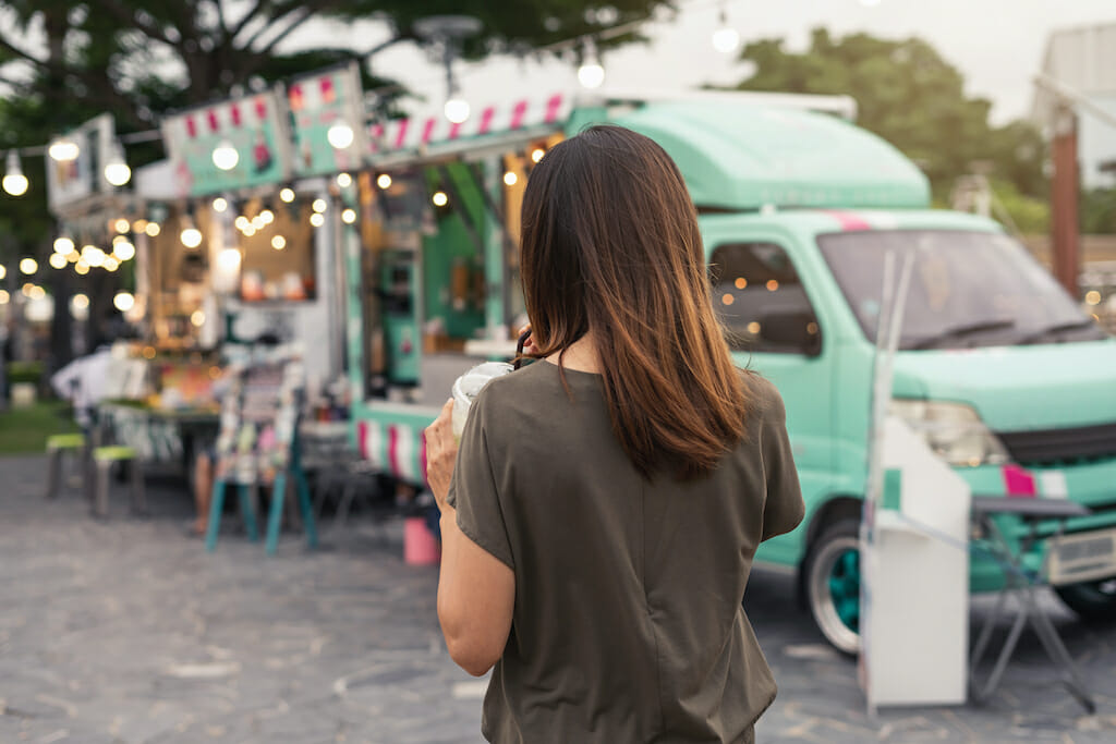 Young asian woman walking in the food truck market