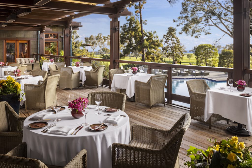 Restaurant tables on covered outdoor patio overlooking pool and golf course. Easter Brunch spots San Diego, The Lodge At Torrey Pines, A.R. Valentien.