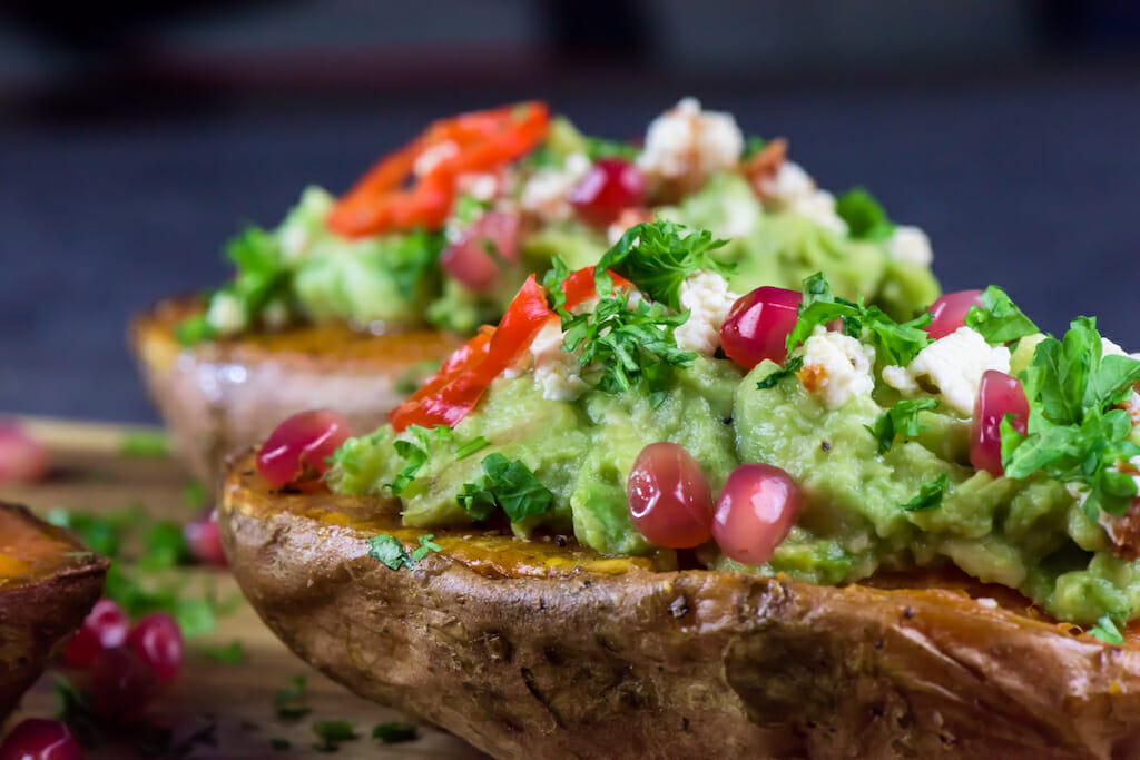 Baked sweet potatoes with guacamole, feta cheese and pomegranate