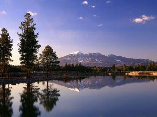 sunset photo of lake in the front, and snow-capped mountains in the back, reflecting in the lake