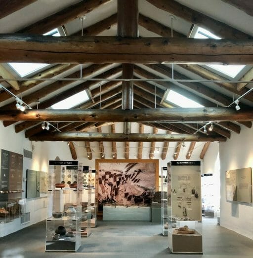 Interior of the Museum of Northern Arizona with Exposed beams up top and exhibits along the wall and in glass show cases in the room