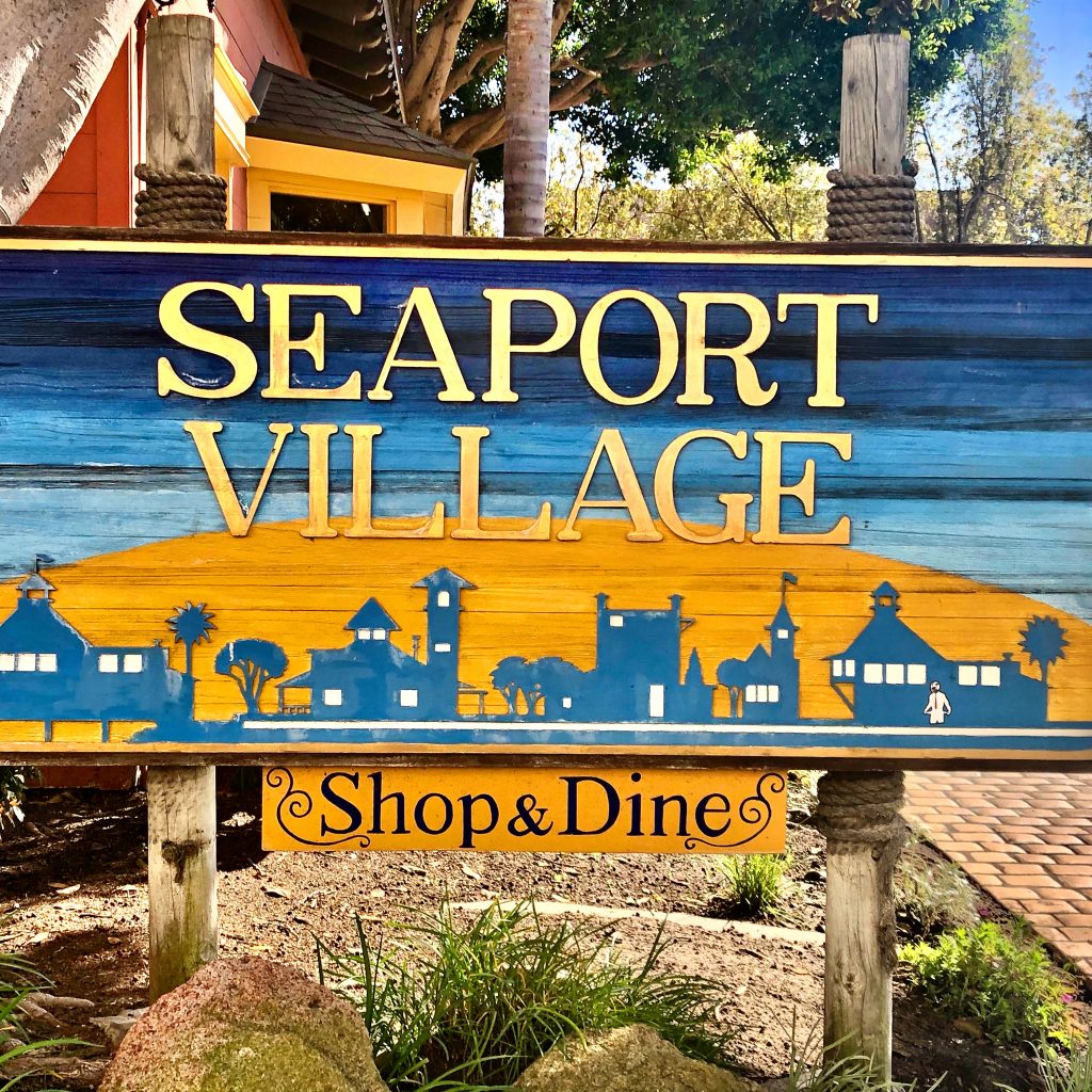 Wood sign in yellow and blue for Seaport Village in San Diego Staycation