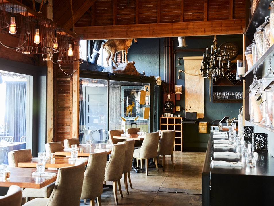 Interior of restaurant with cozy, upscale interior, exposed wood, plush chairs, and natural lighting. The Smoking Goat Restaurant.