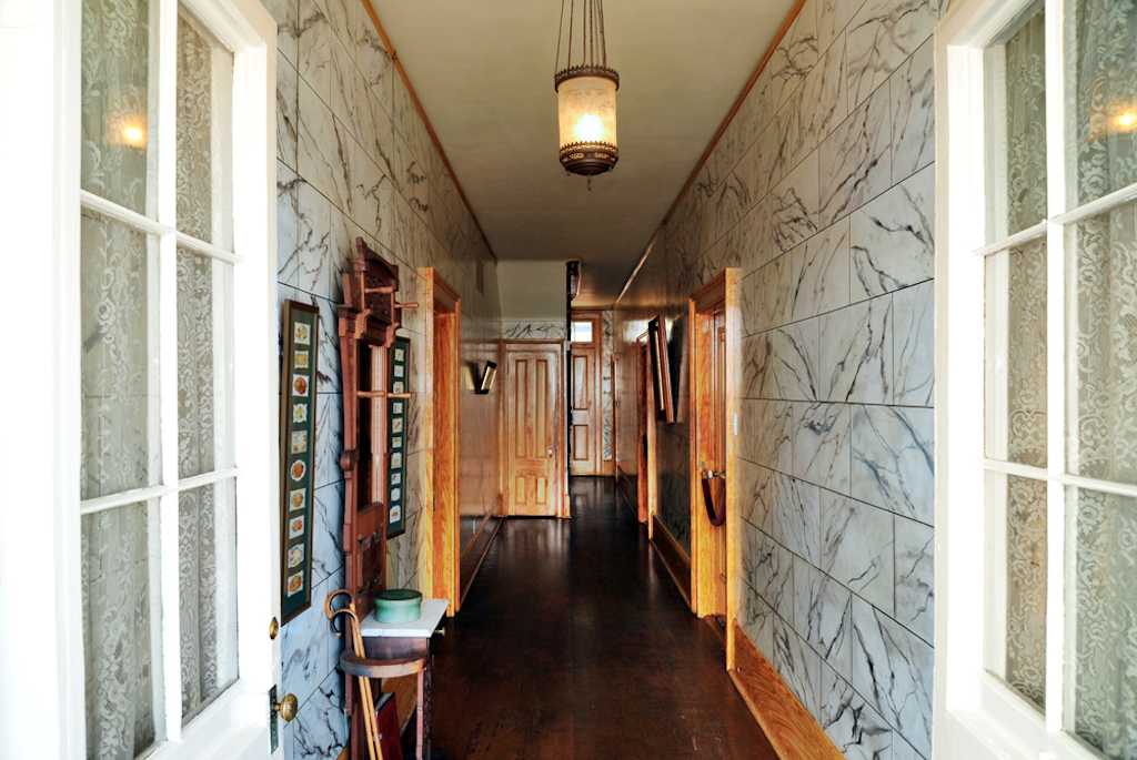 A long marble entry way hall with lights and light wood adornments