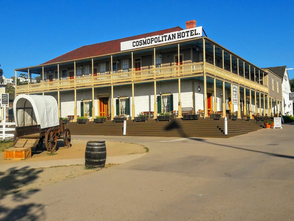 Old Comopolitan Hotel on a bright sunny day in Old Town, San Diego, CA with an old carriage in front of it